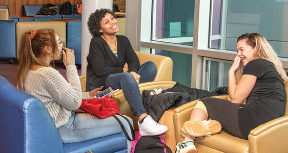 Three FLCC students laughing and enjoying themselves in a campus lounge.