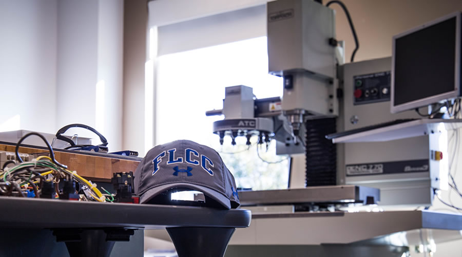 FLCC hat with large scale CNC milling machine in background