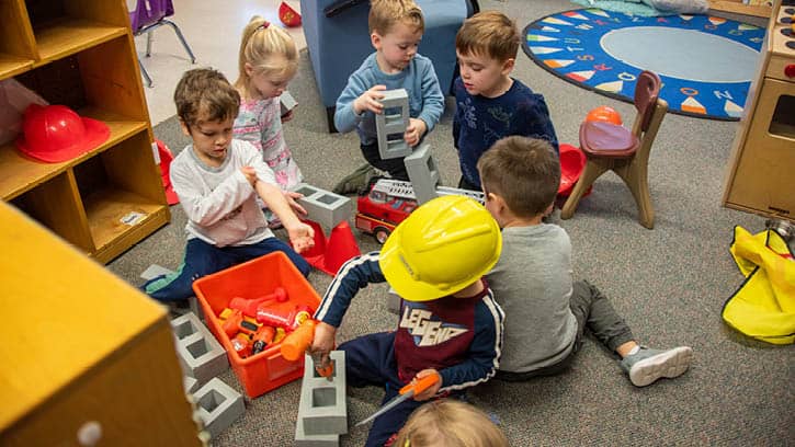 A group of children playing with toy tools and foam bricks.