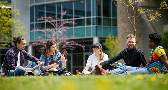 A group of students sitting in the grass outside FLCC's main campus.