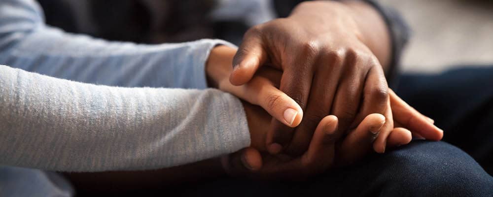 Three hands clasped together in a display of strength, support, and human connection.