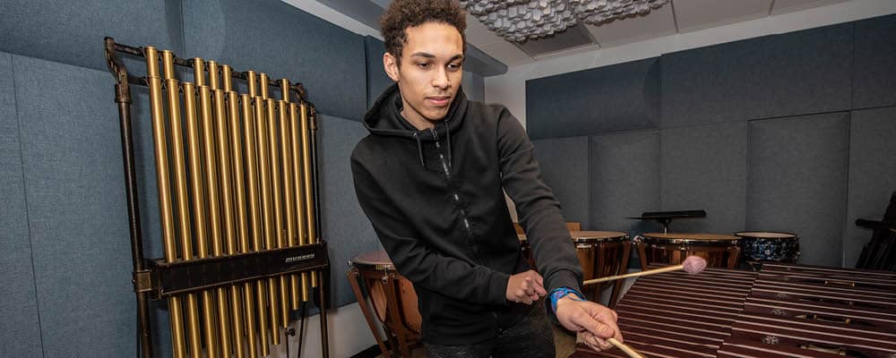 Student playing a xylophone in one of our five music recording studios.
