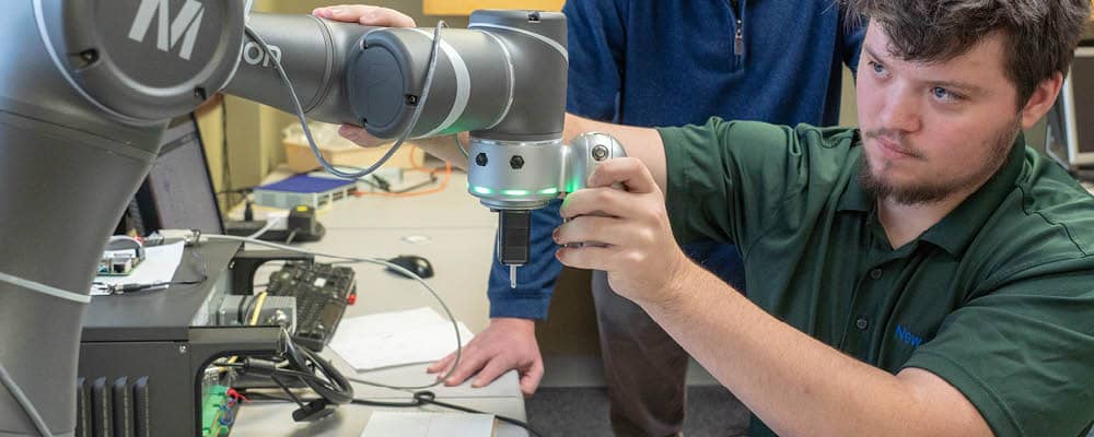 A Smart Systems Technology student working with tablet-controlled robotic equipment.