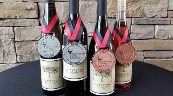 The 2020 Persevere vintage displayed with two silver and two bronze medals from the New York Wine Classic.